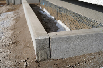A close-up photo of a freshly concreted curb by a house. We can also see the studded foil.