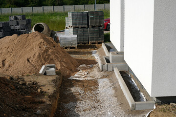 Outdoor environment of a new building. We see a mixer, a pile of sand and other building materials.