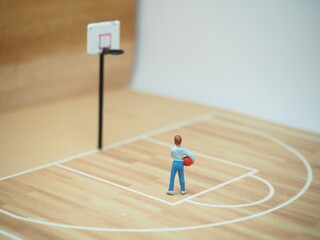 Mini toy of action figure at table with blurred background. Macro toy photography concept design. Minifigure of basketball player character at basketcourt.