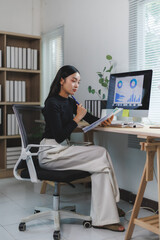 Businesswoman analyzing charts and reports on computer in modern office