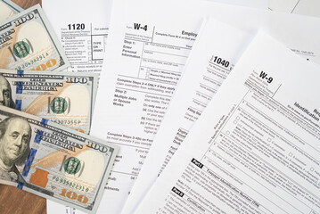 Dollar banknotes lie on different tax forms mandatory for law-abiding taxpayers and business to...