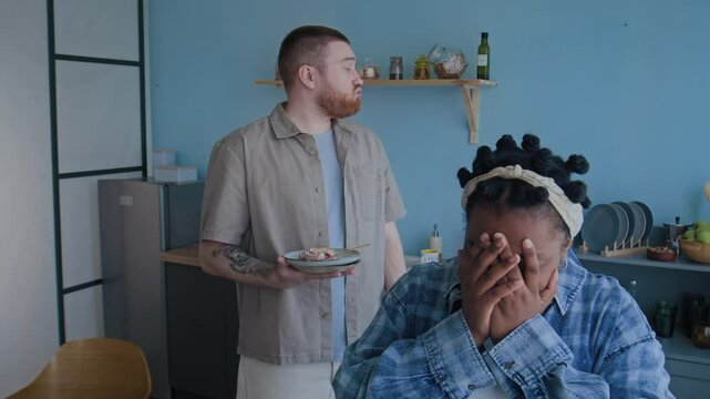 Biracial couple quarreling over cooking, Caucasian man scolding his Black wife while she crying