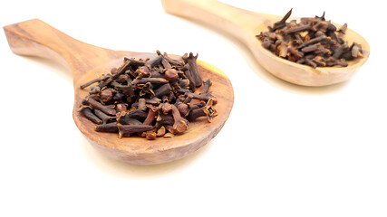 Cloves in wooden spoons isolated on white background, herbs and spices