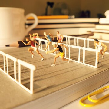 Mini toy of action figure at table with blurred background. Diorama miniature photography concept design. Minifigure of people character at office desk with book and pencil.
