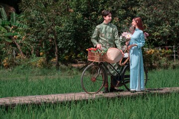 Young Couple in Traditional Attire with Bicycle in Vietnamese Rice Field