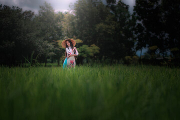 Obraz premium Vietnamese Girl in Traditional Attire Standing in a Rice Field