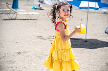 The back shot of  Japanese girl in yellow dress holding a mason jar of juice while walking along...