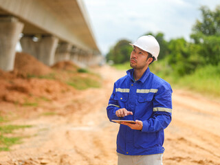 Asian engineer working with tablet at site of a large building project,Thailand people,Work overtime at construction site