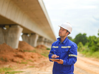 Asian engineer working with tablet at site of a large building project,Thailand people,Work overtime at construction site