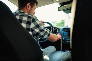 Man sitting in car and pressing engine start button. Starting vehicle using modern ignition...