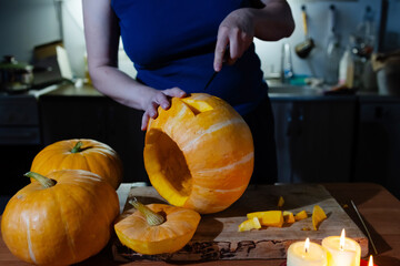 A person carves a pumpkin in a warm kitchen, preparing for Halloween festivities. Nearby, other...