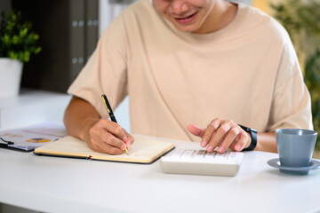 Young man calculating finances and managing expenses at home