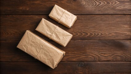 Three brown paper wrapped gifts tied with twine on a dark wood surface present package