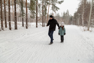 Dad and daughter walking and having fun in snowy winter forest