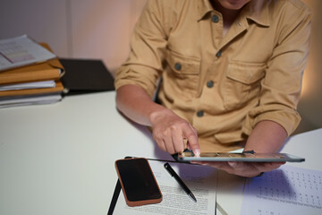 Businessman working overtime, analyzing data on a digital tablet at his office desk