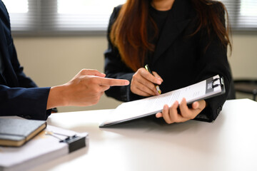 Business partners pointing to details in agreement document during negotiation.