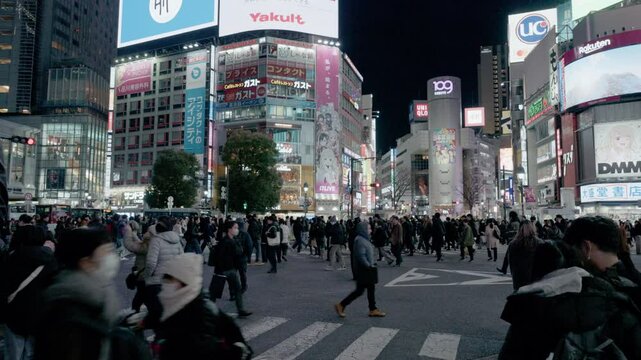 Tokyo, JAPAN, Feb 15th, 2025 &ndash; Crowd of pedestrians crossing Shibuya Scramble intersection at night with illuminated buildings, traffic, and city lights.