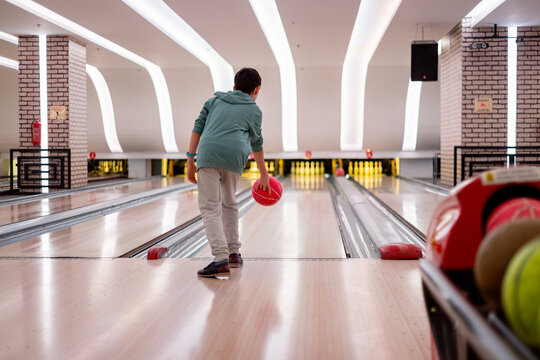 Son playing bowling in a modern bowling alley