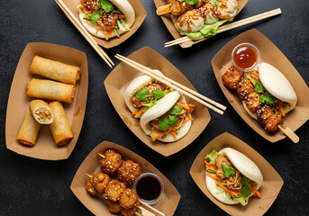 Street food feast with assorted Asian dishes in takeaway boxes. Ideal for food delivery, multicultural cuisine, and restaurant marketing.