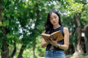 Young woman reading a book in a lush green park