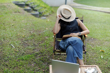 Young woman relaxing with book and laptop in a peaceful park