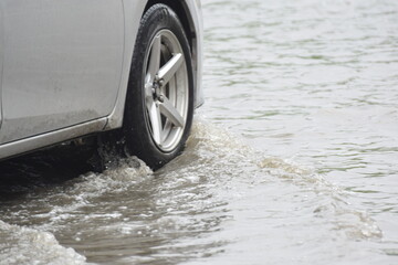 Car passing through a flooded road, flood caused by torrential rains. Flooded city road with a...