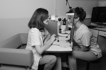 Female doctor examines young womans eye using professional vision testing equipment in clinic