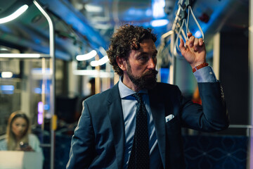 Businessman commuting by public transport standing on a modern bus or tram
