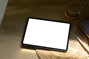 Minimalist workspace scene with digital tablet, coffee cup, and natural warm light