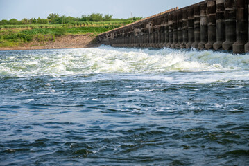Rapidly flowing water with large waves over a dam on a river, water flow at the dam gate