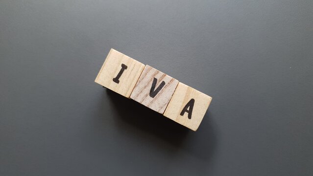IVA acronym made of wooden letter cubes on dark background. Impuesto sobre el Valor A&ntilde;adido (Value Added Tax, VAT)