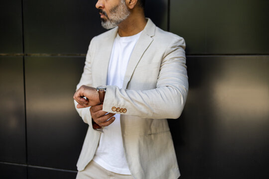 Stylish Indian man checking time in summer attire