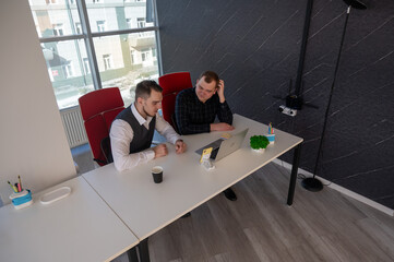 Two Caucasian men sitting at a table and discussing work. 