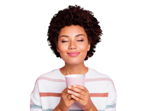 Photo of pretty dark skin lady holding in hands hot beverage cup dreamy closing eyes enjoy good smell wear striped pullover isolated pastel pink color background