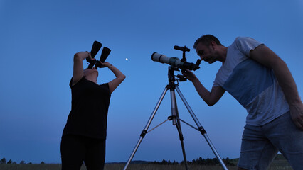 Amateur astronomers using telescope and binoculars for watching stars, Moon, planets and other...
