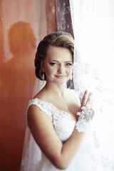 A woman in a white dress is posing for a picture with her hand behind her back. She is smiling and...