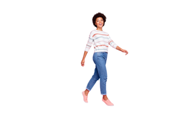 Full body profile photo of pretty dark skin lady walking down street enjoy amazing warm fall weather wear striped pullover and jeans isolated pastel pink color background