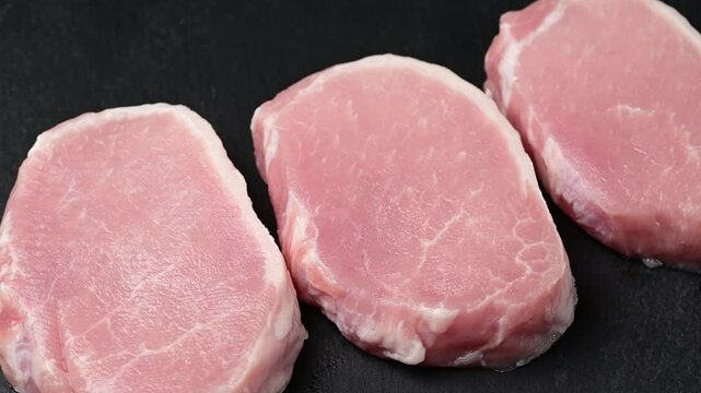 Preparing fresh pork escalopes: slicing, arranging, and displaying raw cutlets on black surface