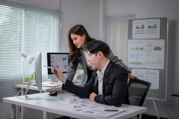 man and a woman are sitting at a desk with a computer monitor in front of them