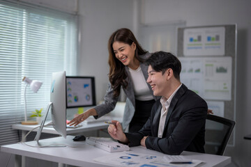 woman and a man are sitting at a desk with a computer monitor in front of them