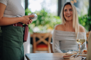 Waitress holding pos terminal for contactless payment in restaurant