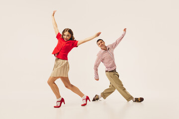 An energetic couple performs retro lindy hop dance in vibrant vintage attire, showcasing dynamic...