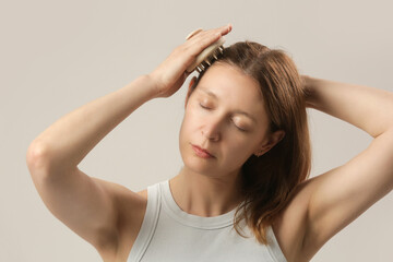 Girl doing herself a head massage using a scalp massager, stimulating hair growth, microcirculation, help to distribute natural oils more evenly across the scalp