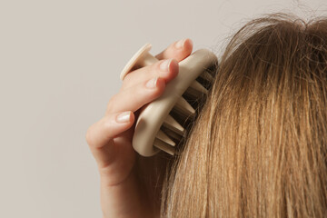 Girl doing herself a head massage using a scalp massager, stimulating hair growth,...