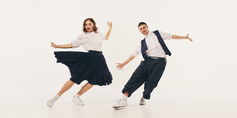 Retro lindy hop dancers perform in dynamic motion against a plain backdrop. Concept of vintage...