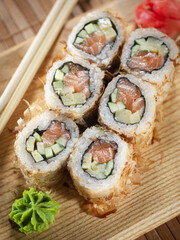 A sushi roll with cucumber and salmon on top