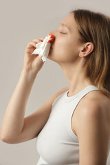 Nosebleed, a young woman with a bloody nose. Healthcare and medical concept. Close up studio image.