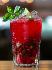 A glass of red drink with a lime garnish