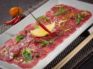 A plate of meat with a lemon wedge and a chili pepper on top