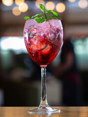 A glass of pink drink with a green leaf on top
